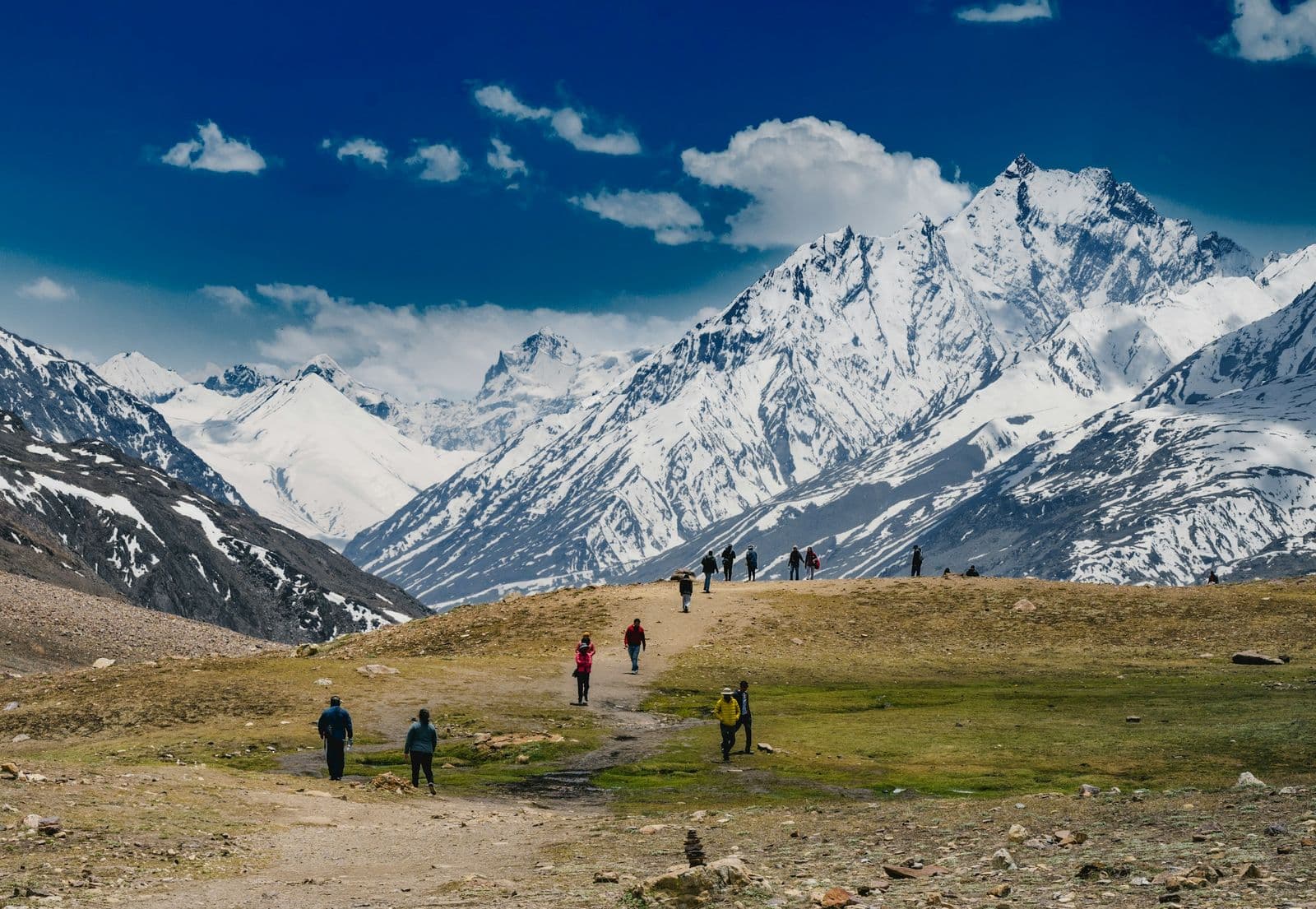 A group hiking toward snowy mountain peaks